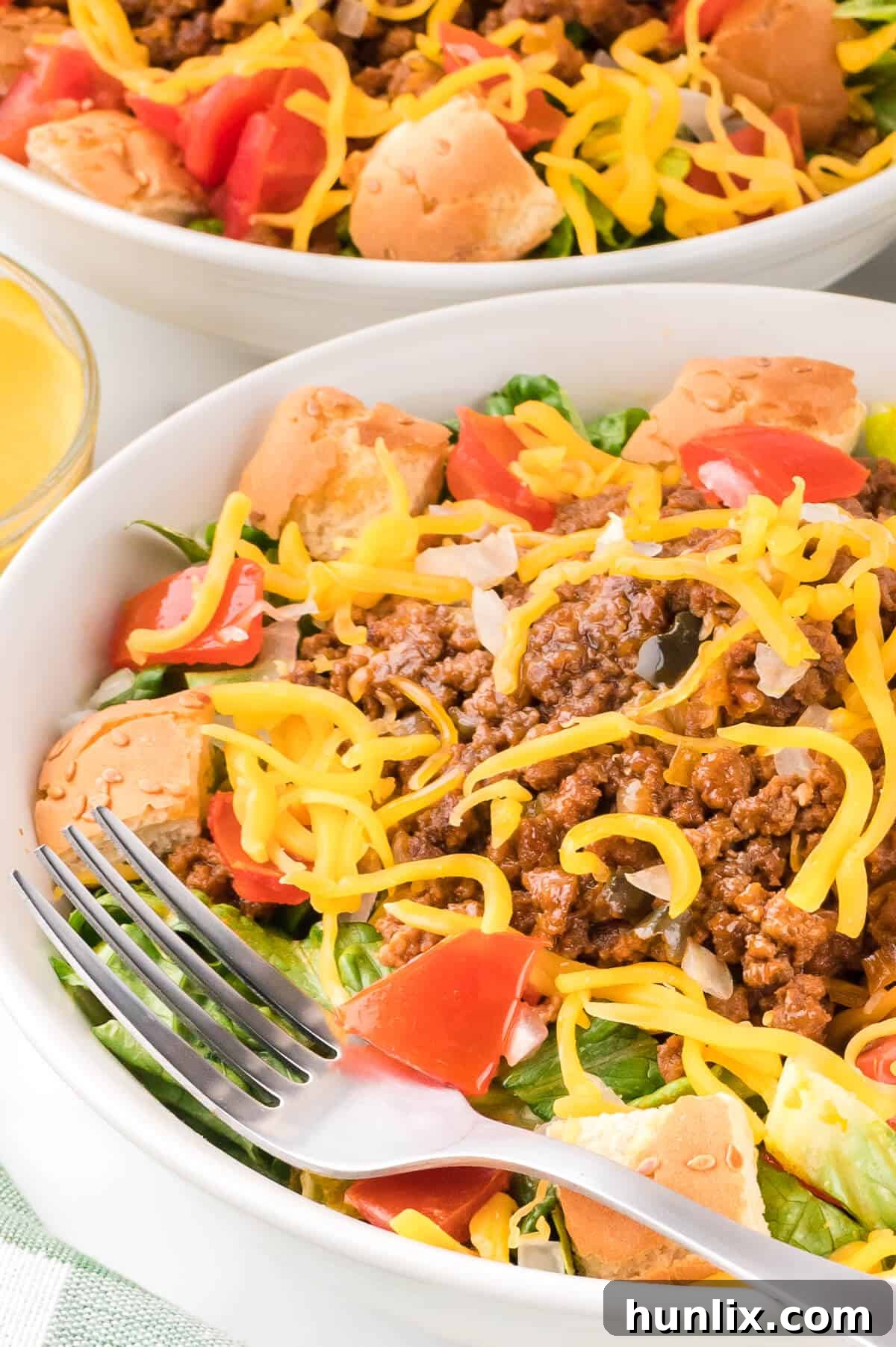 Cheeseburger in a Bowl 8 A fork lifting a delicious bite of cheeseburger salad, highlighting the layers of ingredients including juicy beef, cheese, and fresh greens.