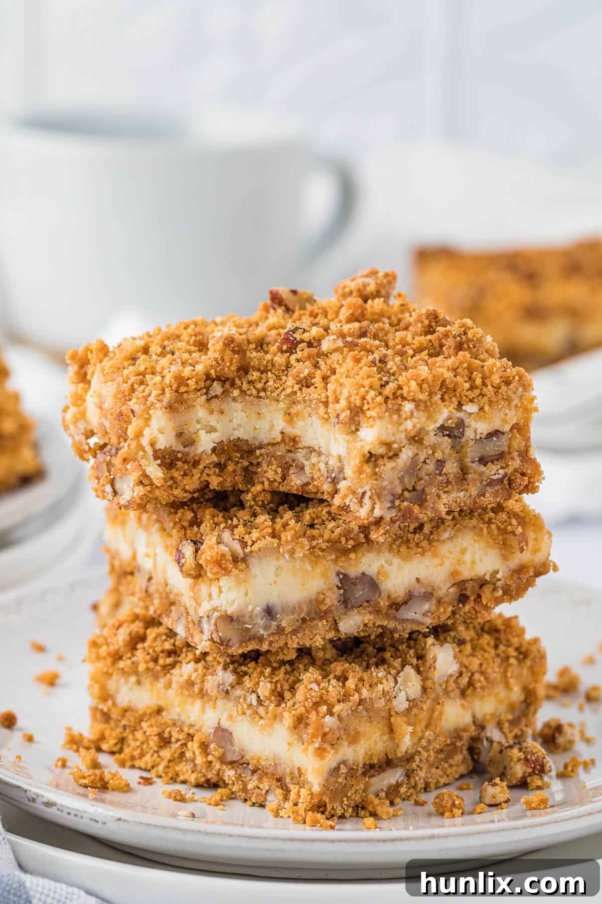 Dreamy Butterscotch Cheesecake Squares 2 A stack of golden brown butterscotch cheesecake bars on a white plate, highlighting their creamy texture and crumbly topping.