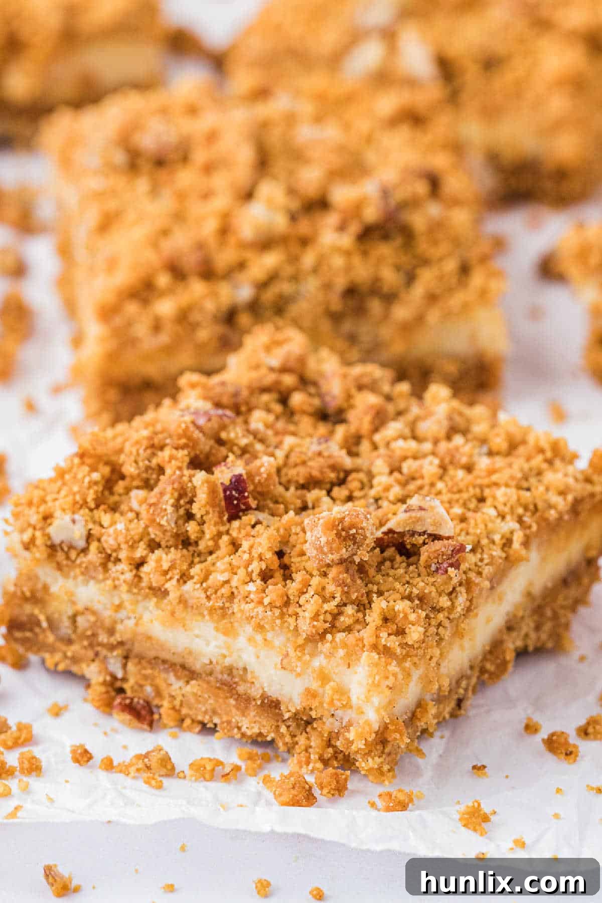 Dreamy Butterscotch Cheesecake Squares 7 A close-up of a butterscotch cheesecake bar on a piece of parchment paper, showcasing its smooth filling and crumbly topping.