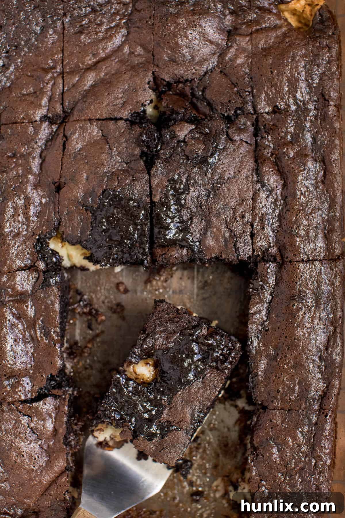 A pan of earthquake cake with some slices cut out and one piece on a spatula.