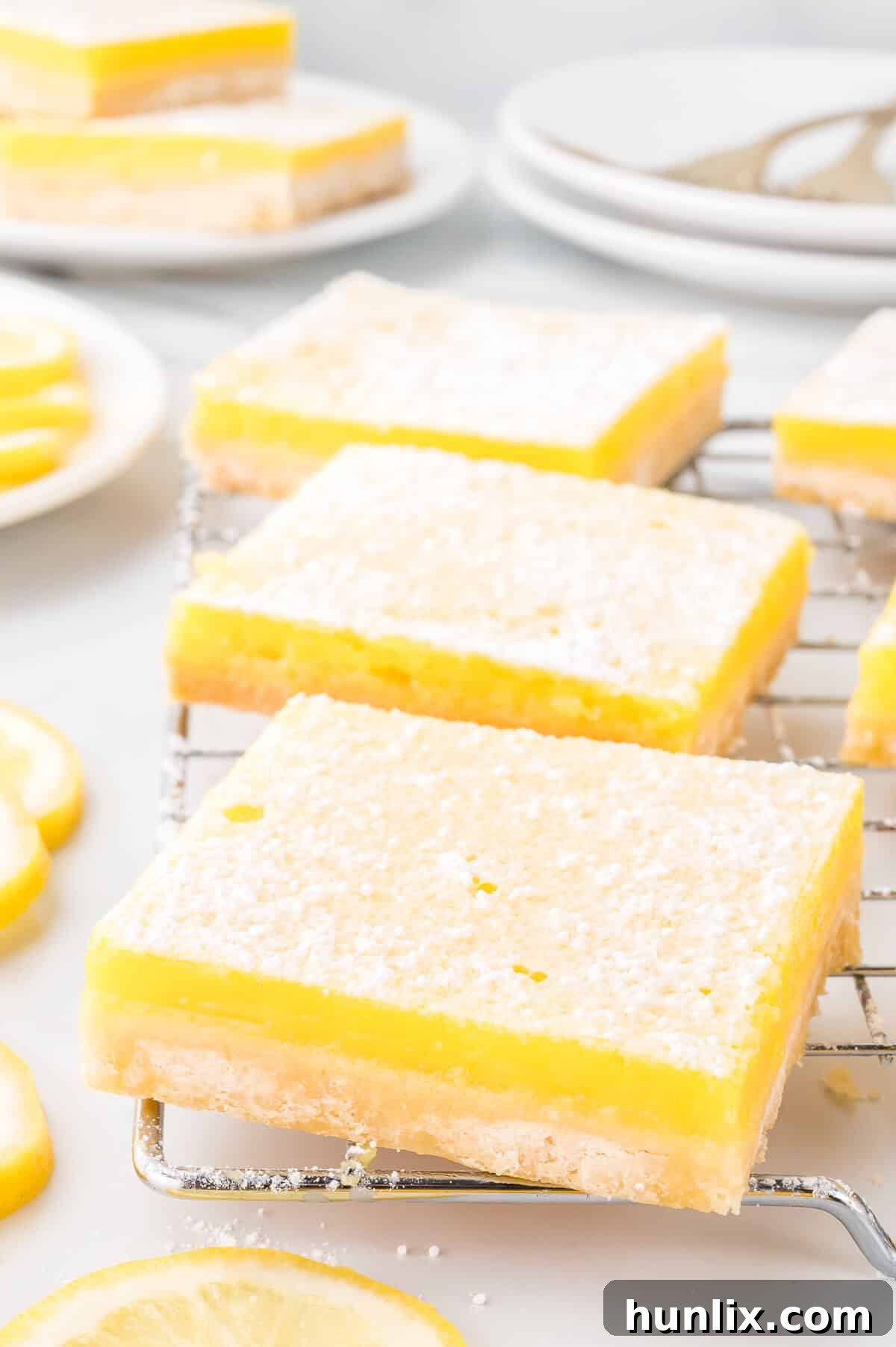 Golden lemon bars dusted with powdered sugar, cooling on a wire rack.