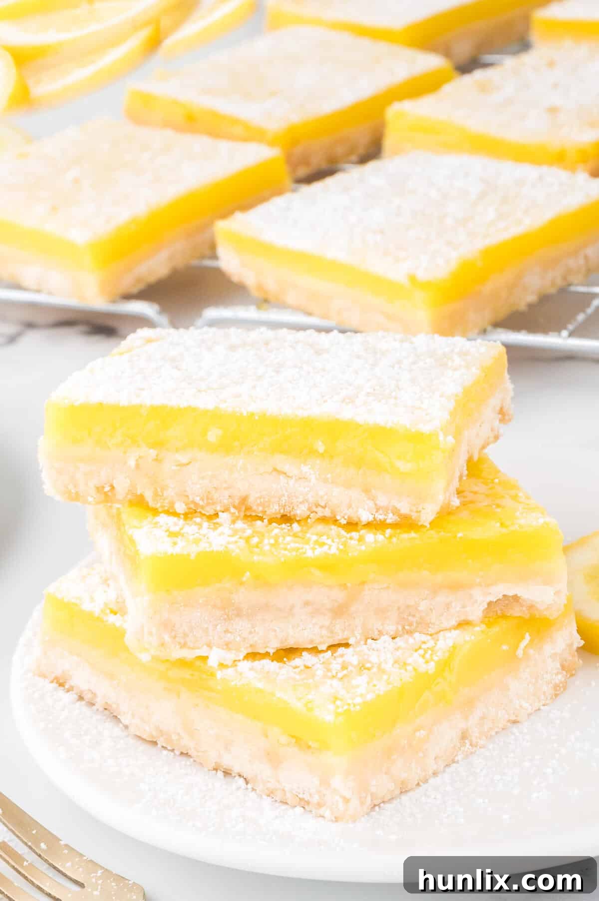 A stack of lemon bars on a white plate, ready to be enjoyed.