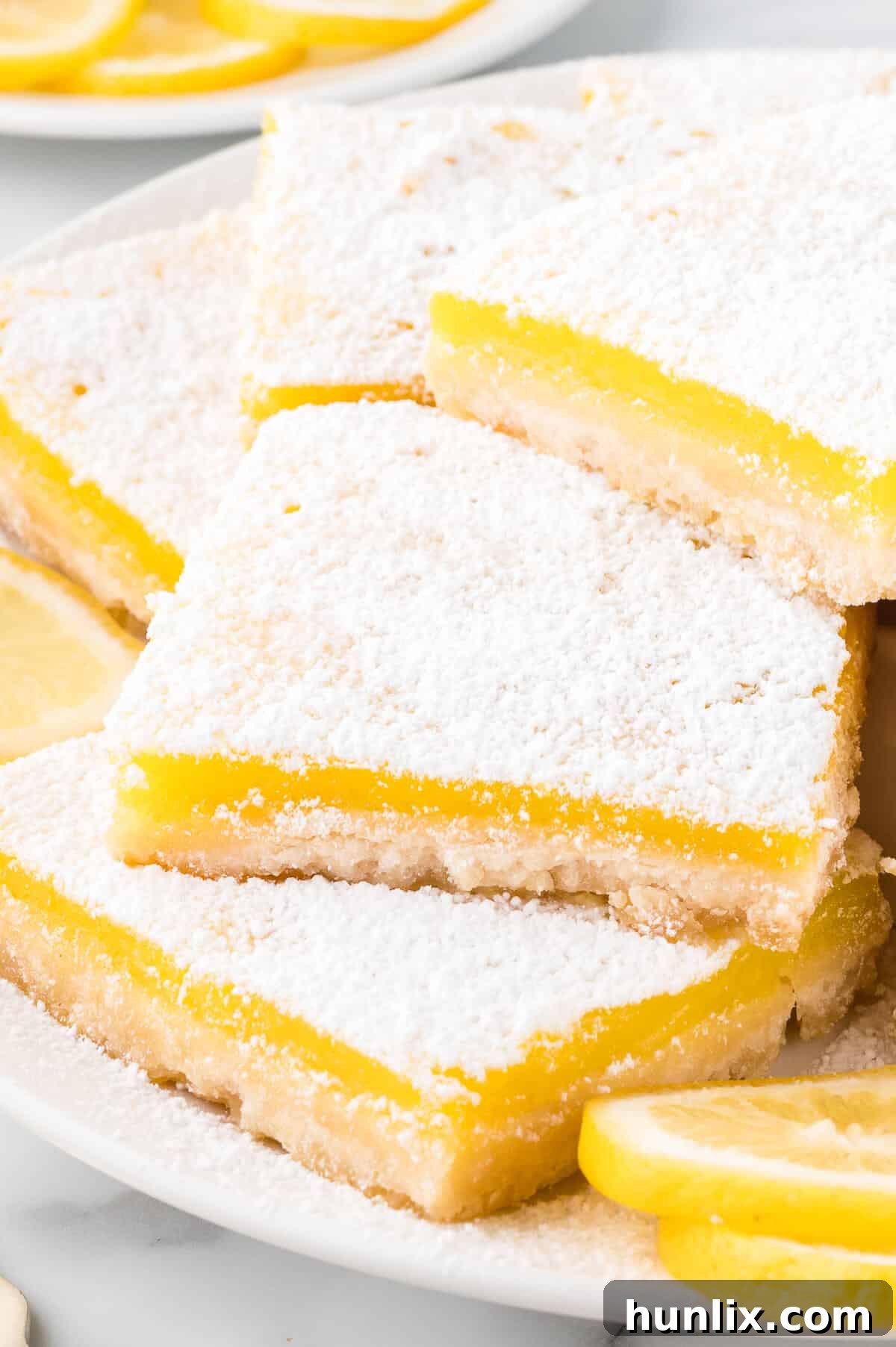 A close-up shot of a lemon bar on a plate, showcasing its layers.
