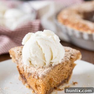A slice on pie topped with vanilla ice cream on a plate.