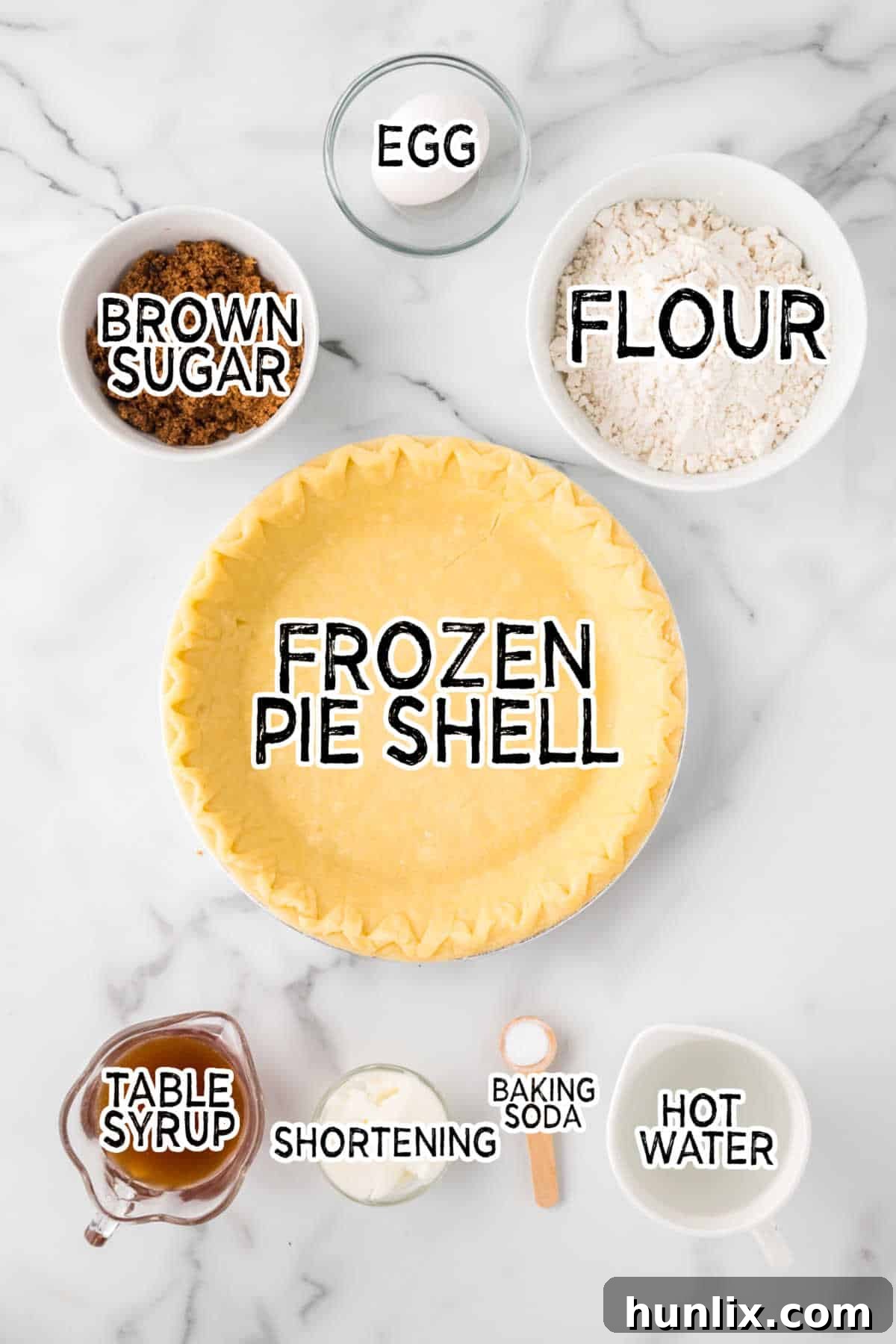 Fresh ingredients for Shoofly Pie, including flour, brown sugar, shortening, syrup, baking soda, and an egg, arranged on a white marble counter.