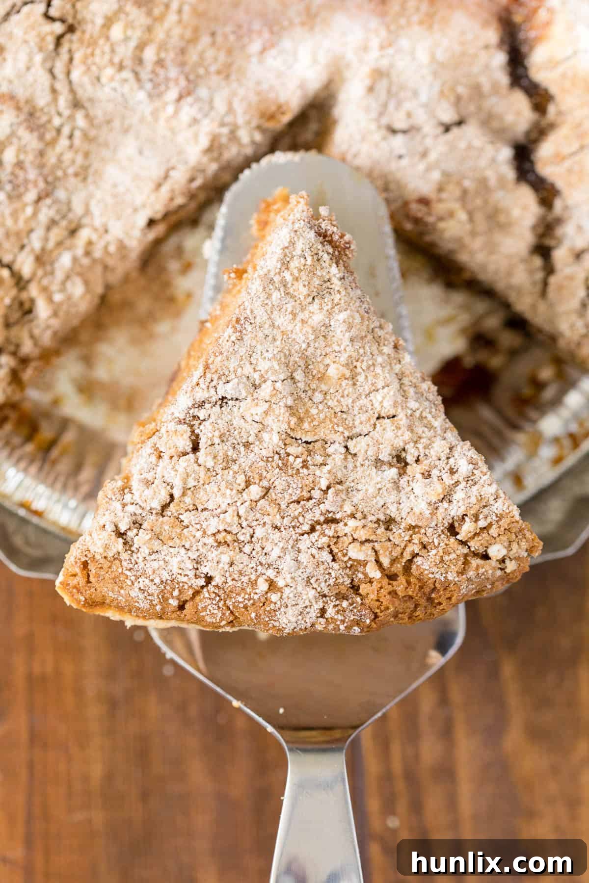 A slice of Shoofly Pie being carefully lifted onto a serving plate with a pie spatula, highlighting its rich, gooey filling and crumbly top.