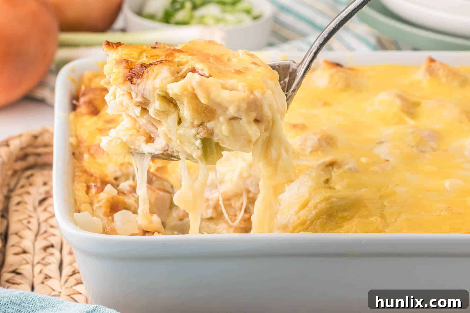 A serving spoon lifting a portion of hot, bubbly chicken cordon bleu casserole from the dish, showing its delicious layers.