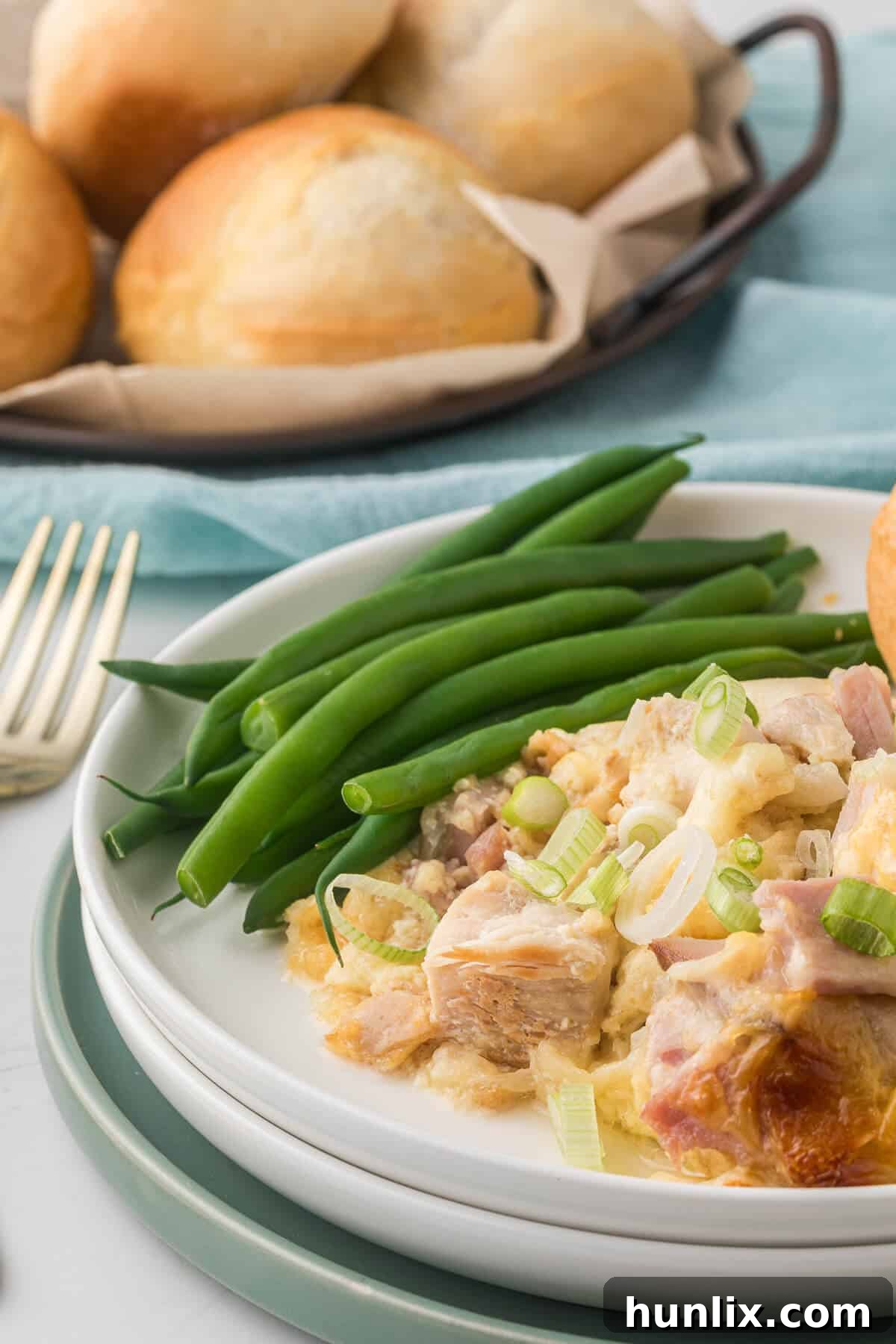 A generous serving of chicken cordon bleu casserole on a white plate, accompanied by vibrant green beans, ready to be enjoyed.