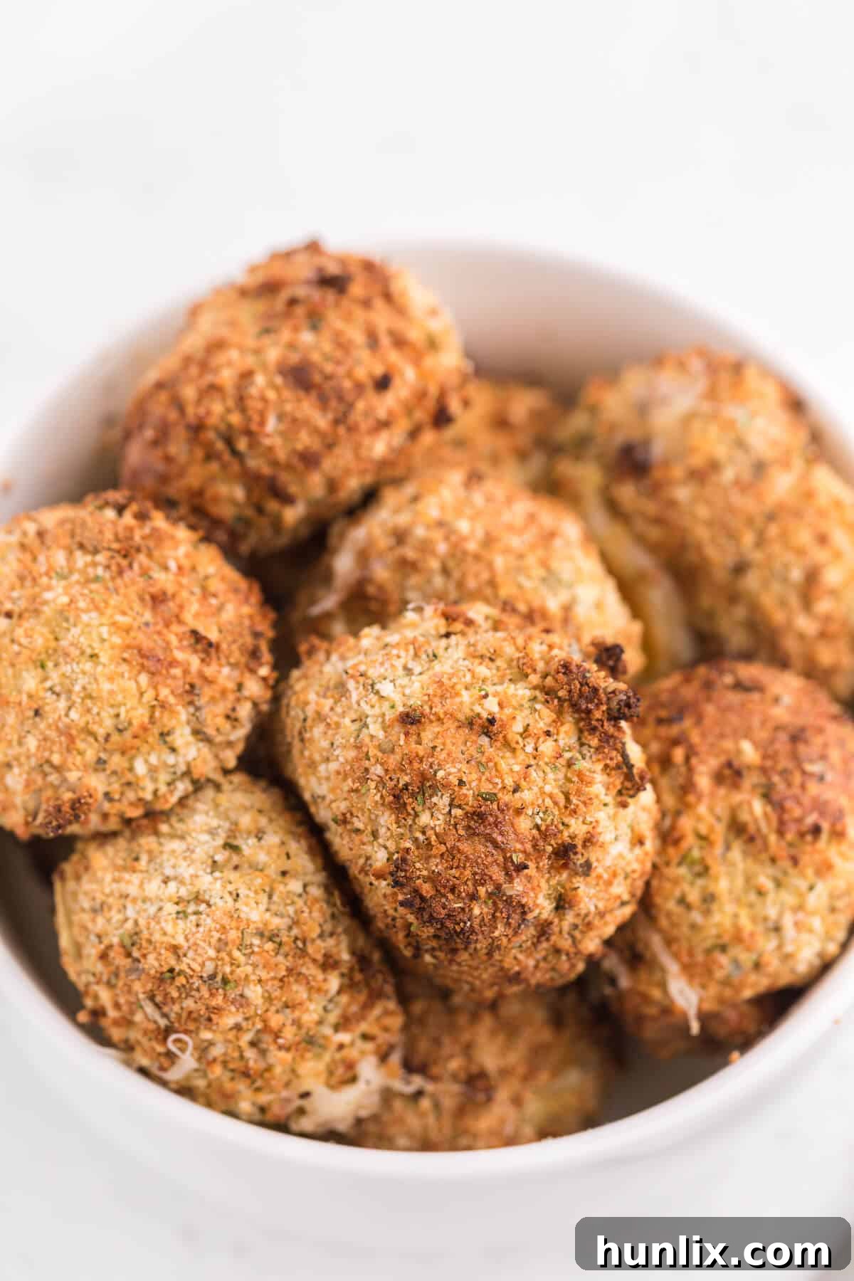 Close-up of crispy air fryer mozzarella balls in a white bowl.
