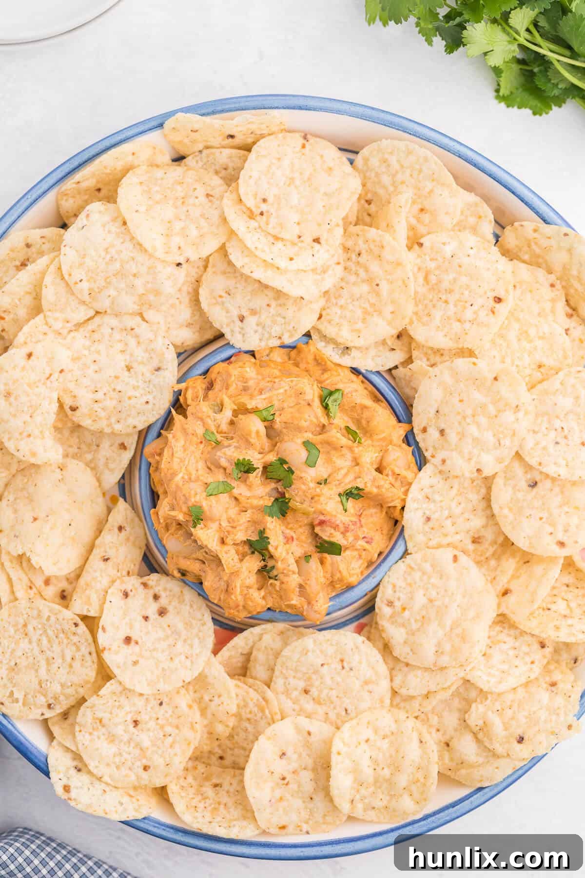 Scooping creamy Crockpot White Chili Chicken Dip with a tortilla chip.