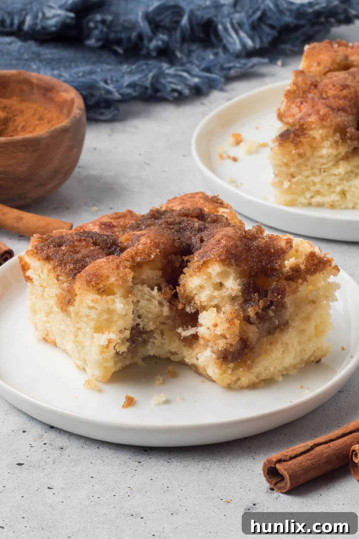 Grandma's Signature Cinnamon Coffee Cake 10 A slice of cinnamon coffee cake with a bite taken out, resting on a white plate, revealing its moist and textured interior.