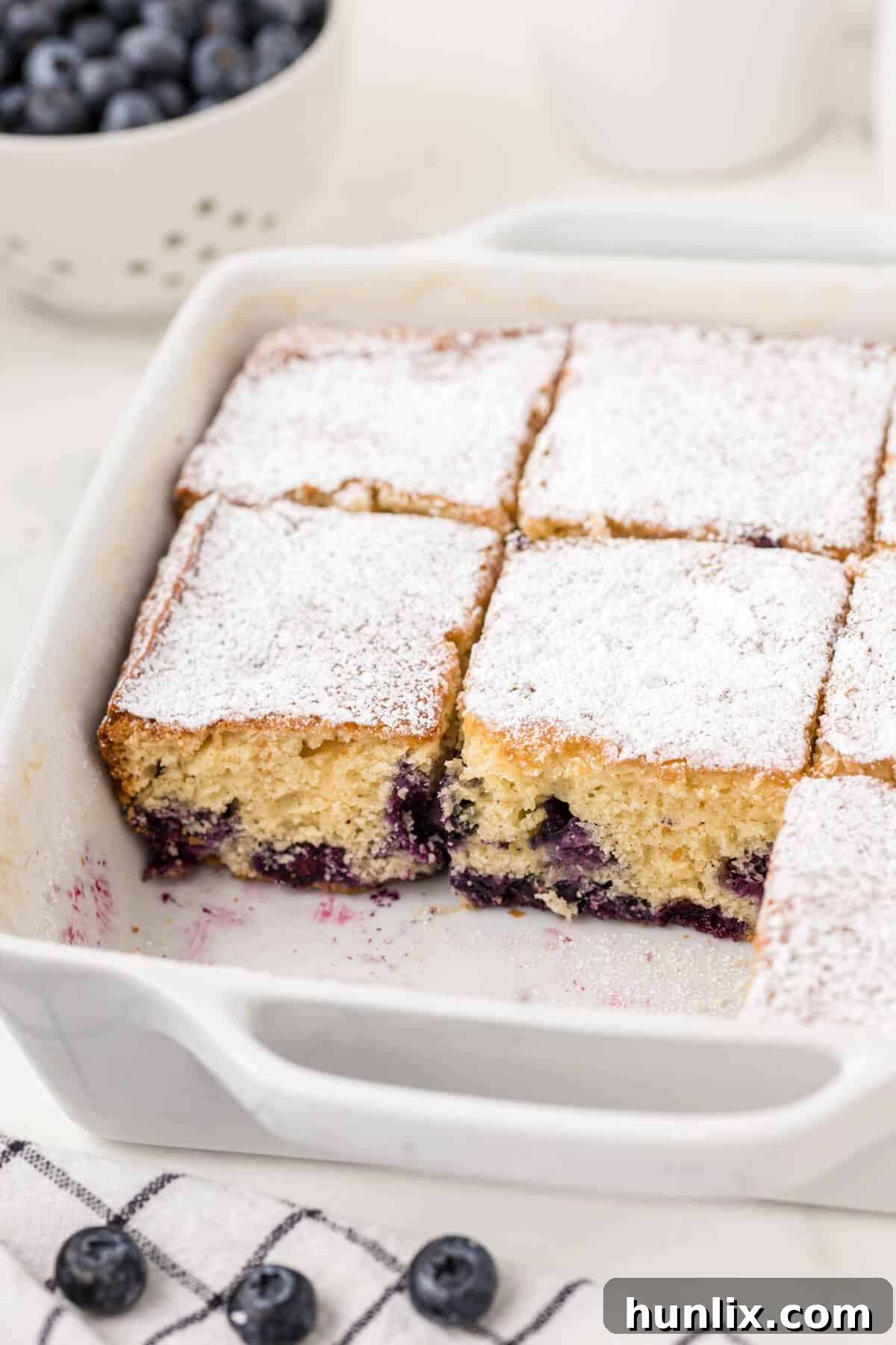 Blueberry tea cake sliced into perfect squares in a baking pan, ready to be served.