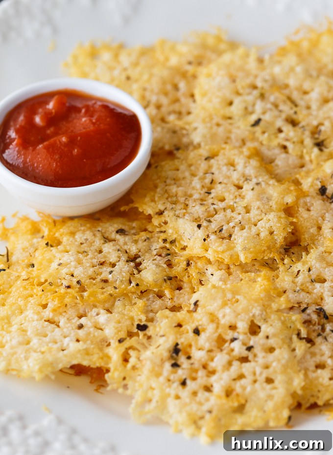 Parmesan crisps served alongside a small bowl of rich pizza sauce for dipping.