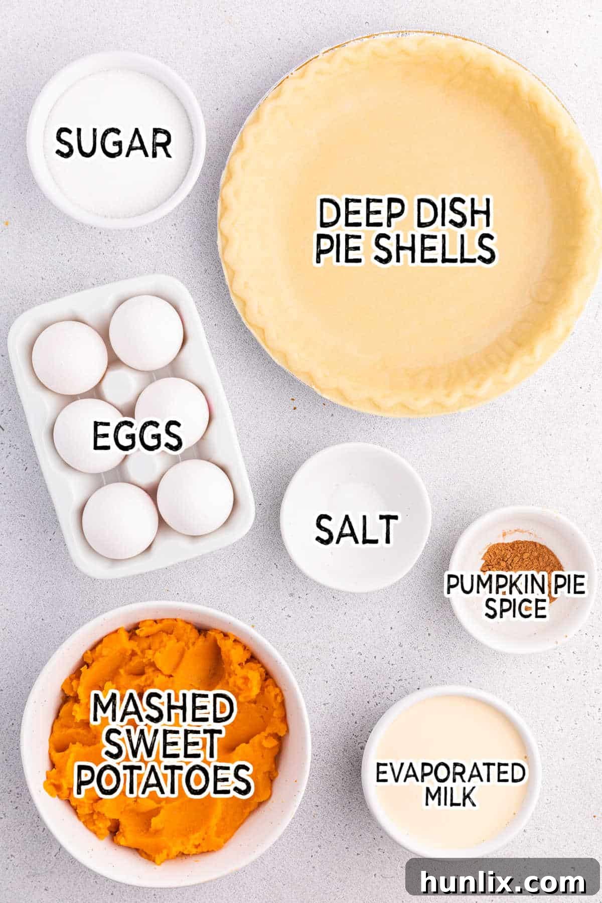 A flat lay photograph showcasing all the fresh and pantry ingredients needed to bake a homemade sweet potato pie.