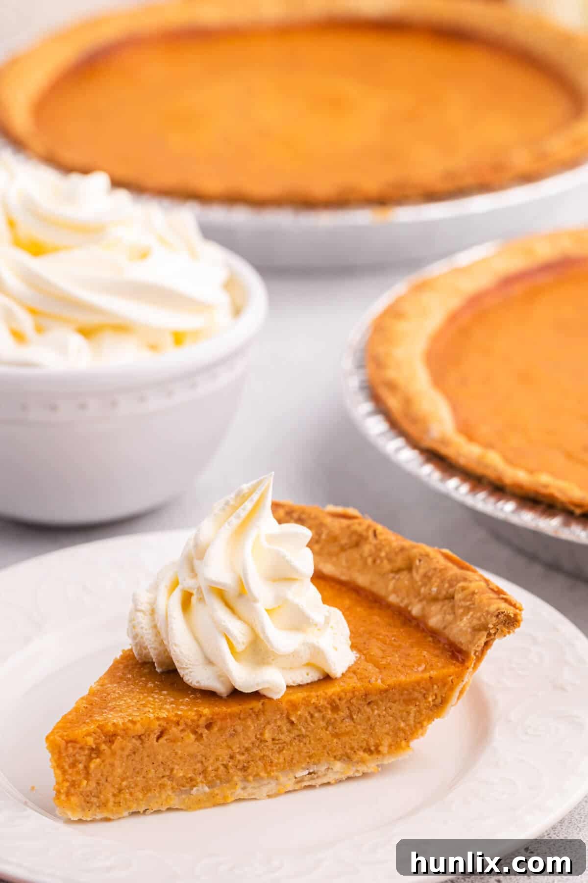 A close-up shot of a sweet potato pie slice, beautifully presented with a dollop of whipped cream on a plate.