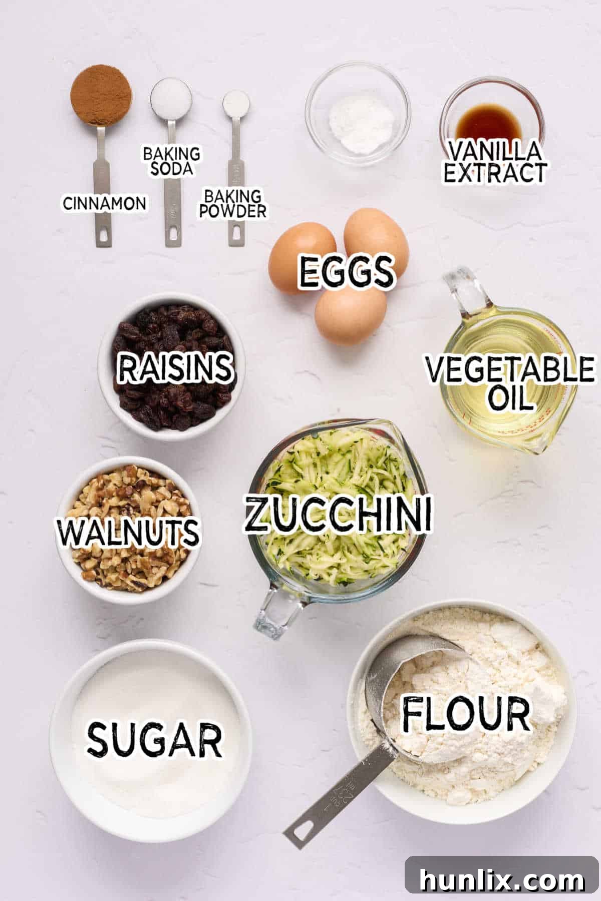 A flat lay image showing all the ingredients for zucchini bread laid out on a surface.