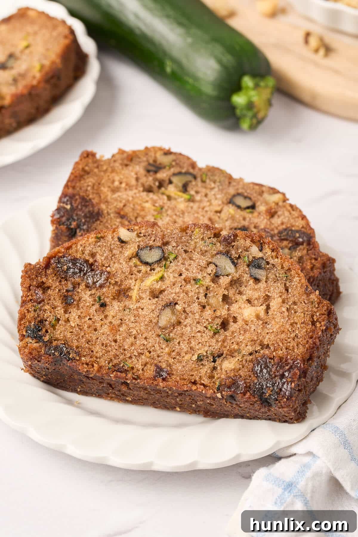 Multiple slices of freshly baked zucchini bread arranged neatly on a white plate, ready to be enjoyed.