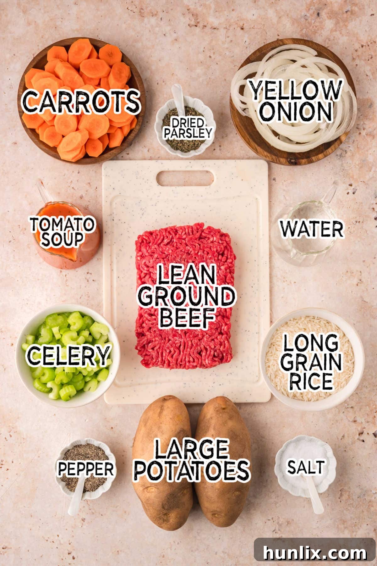 Castaway's Feast 3 A collection of fresh ingredients laid out on a brown background, including onions, potatoes, ground beef, rice, celery, carrots, and a can of tomato soup.