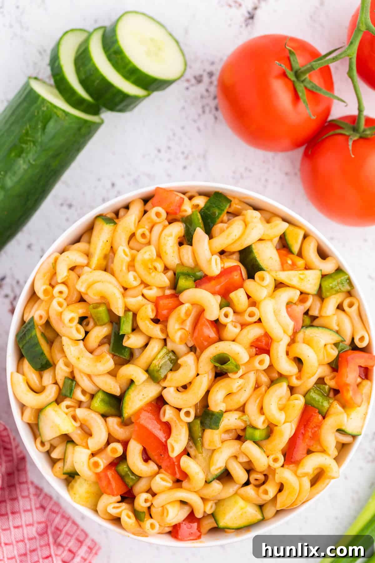 Creamy Pasta Delight 2 A vibrant bowl of sweet and tangy Macaroni Salad, featuring elbow macaroni, chopped tomatoes, green onions, cucumbers, and green peppers, all tossed in a unique ketchup and vinegar-based dressing. Perfect for summer BBQs and picnics.