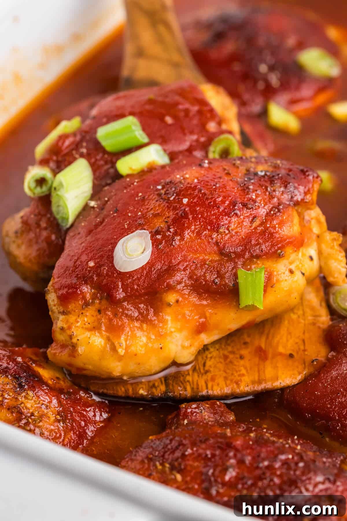 A serving of sweet and sour chicken on a wooden serving spoon, highlighting the saucy, tender chicken.