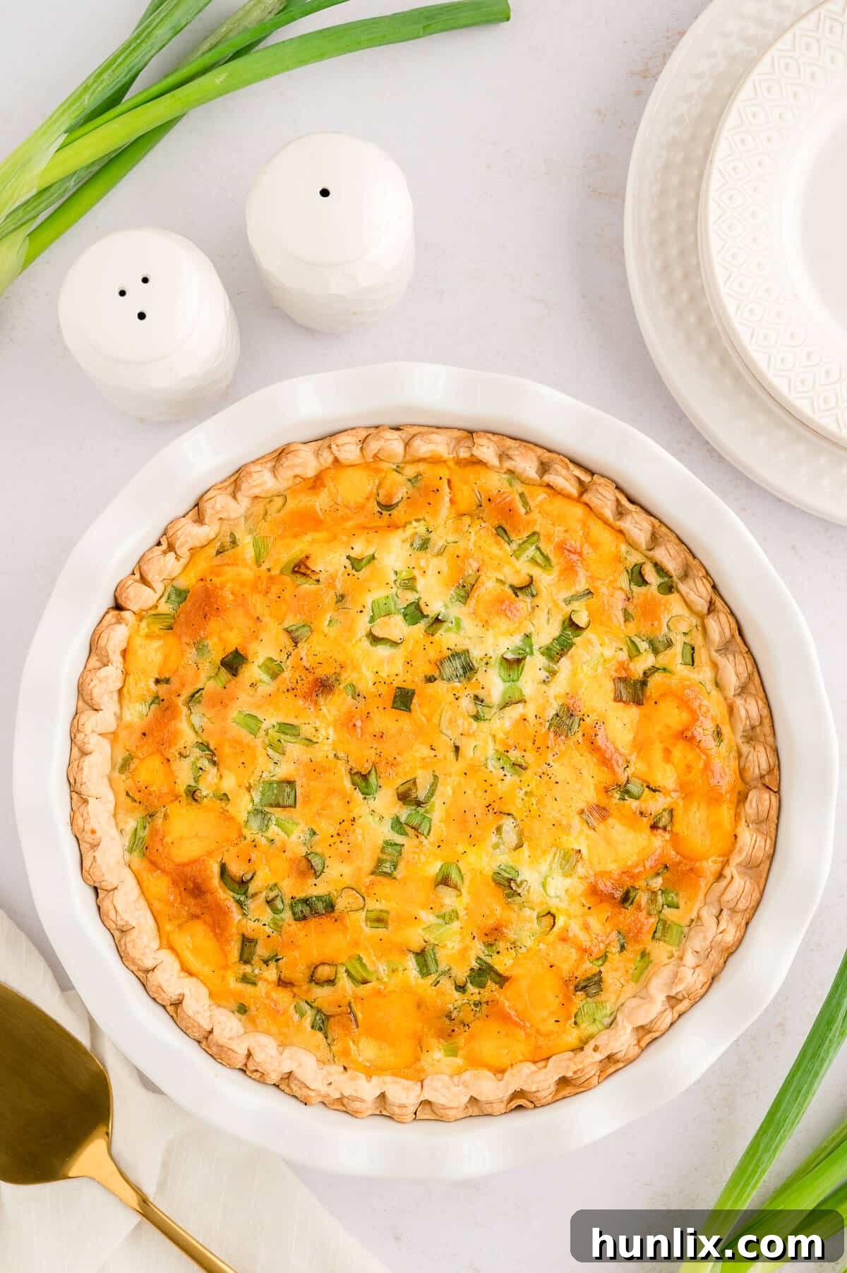 Golden-brown hamburger quiche in a white ceramic pie pan, fresh from the oven.
