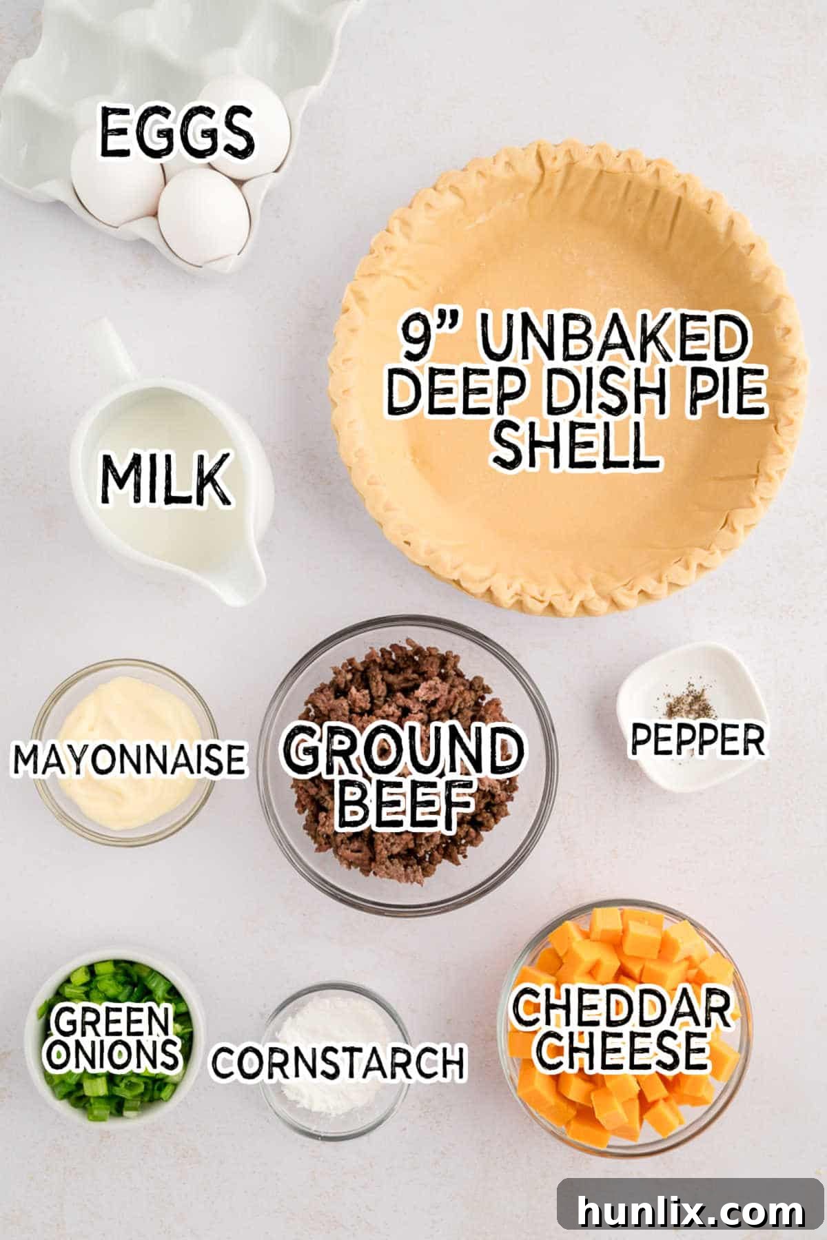 Arrangement of fresh ingredients including ground beef, eggs, cheese, mayonnaise, milk, and green onions for hamburger quiche.