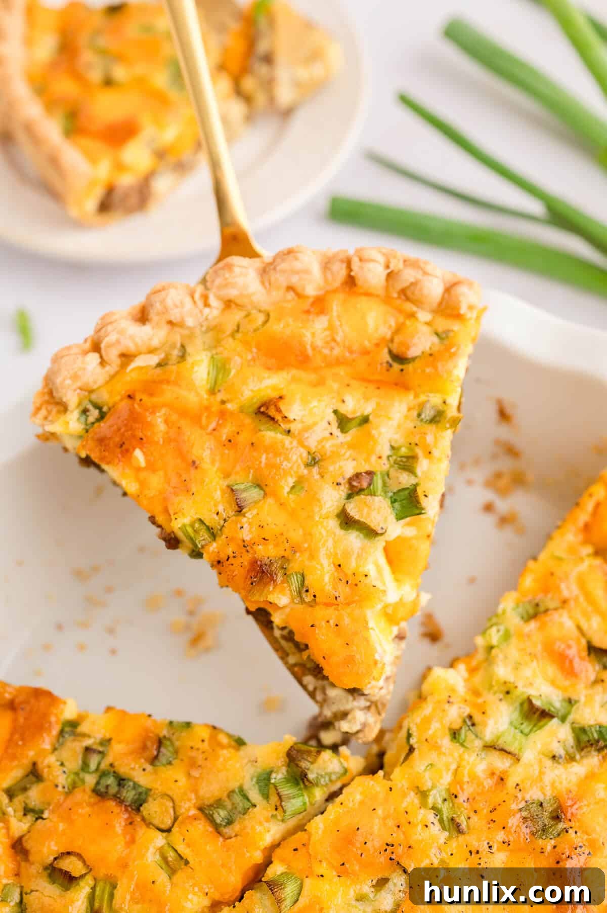 A slice of golden hamburger quiche being transferred with a pie server.