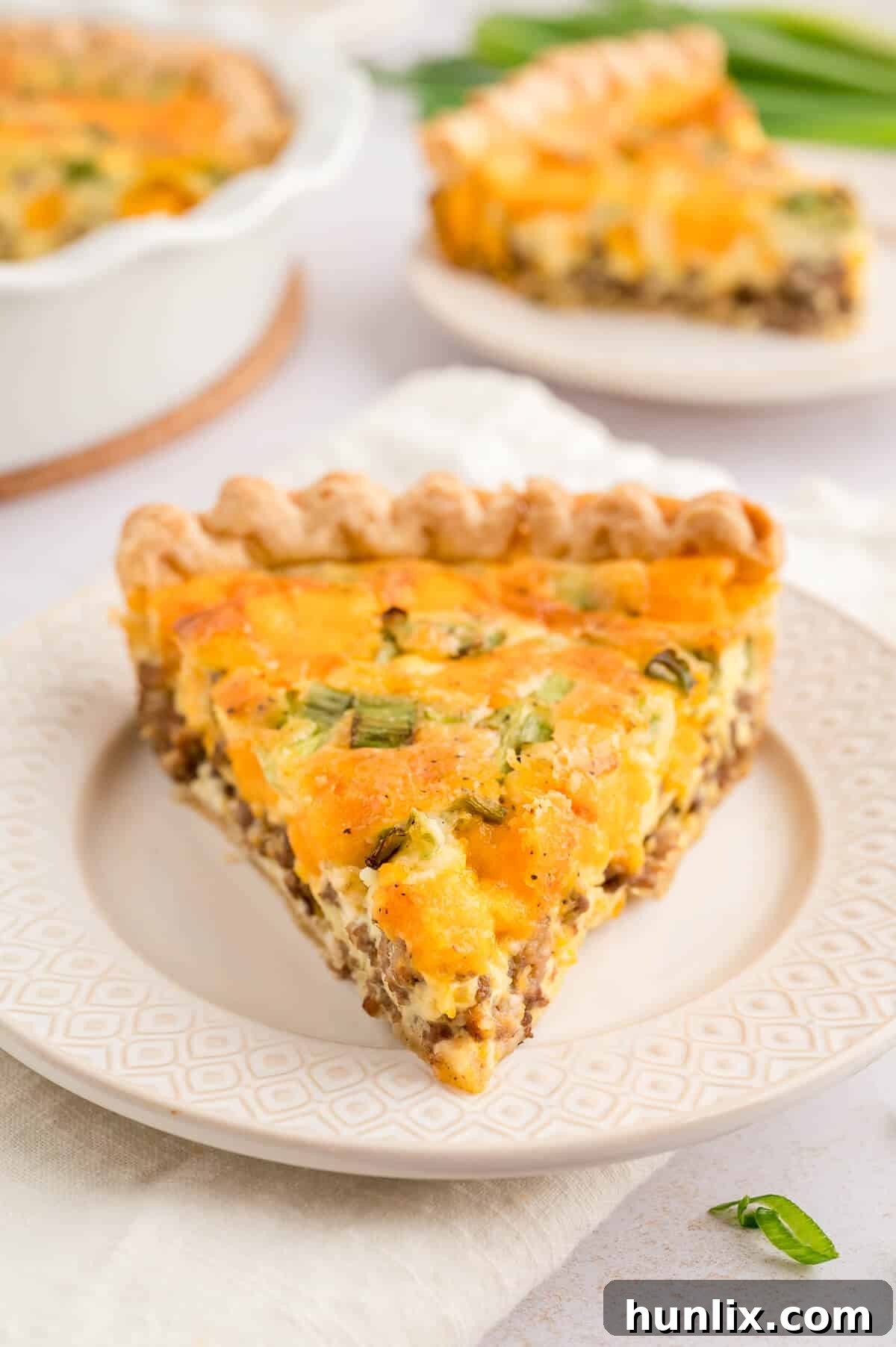 A close-up view of a slice of hamburger quiche on a plate, highlighting the rich filling and crust.
