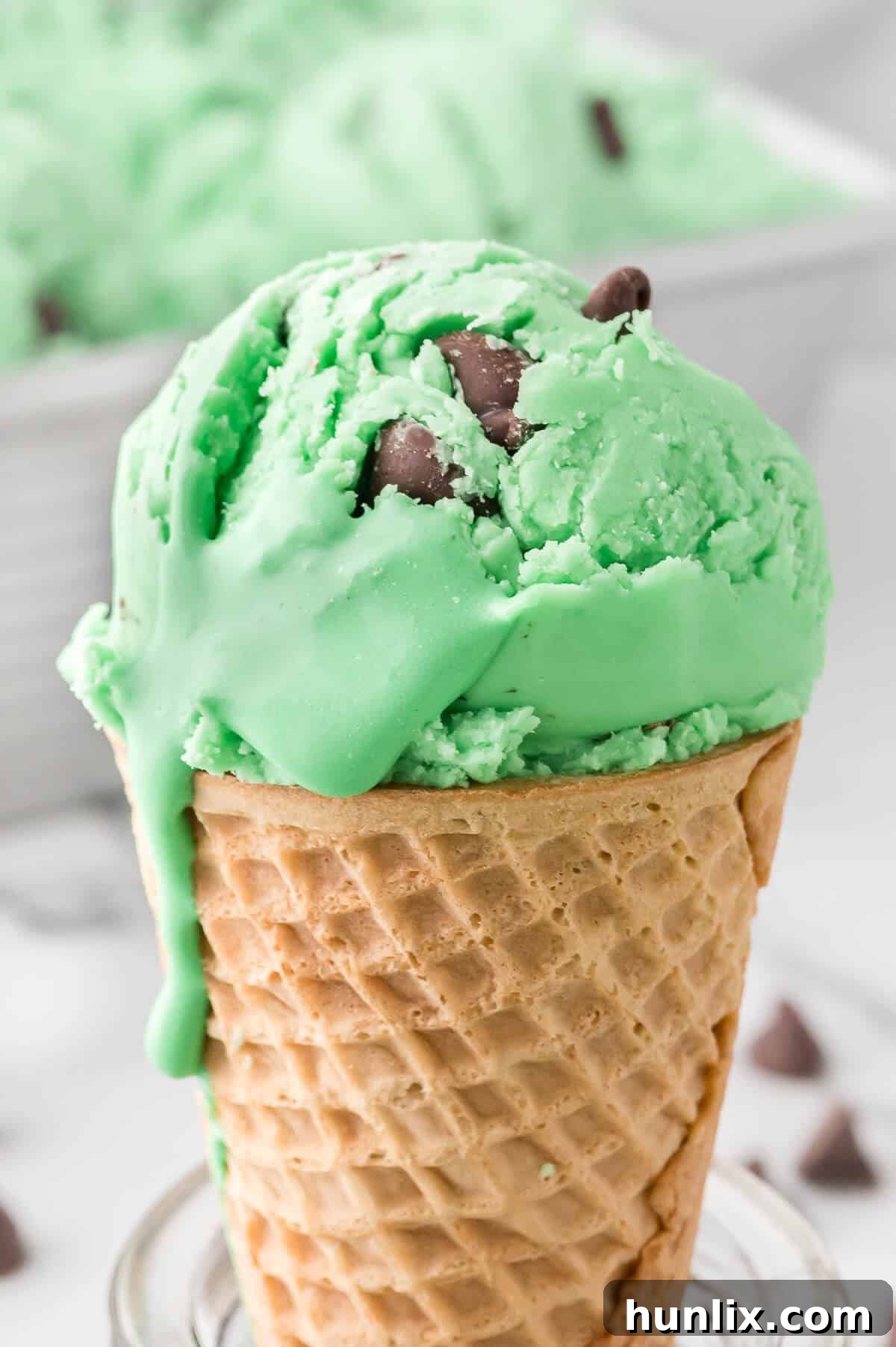 A single scoop of mint chocolate chip ice cream in a crisp waffle cone.