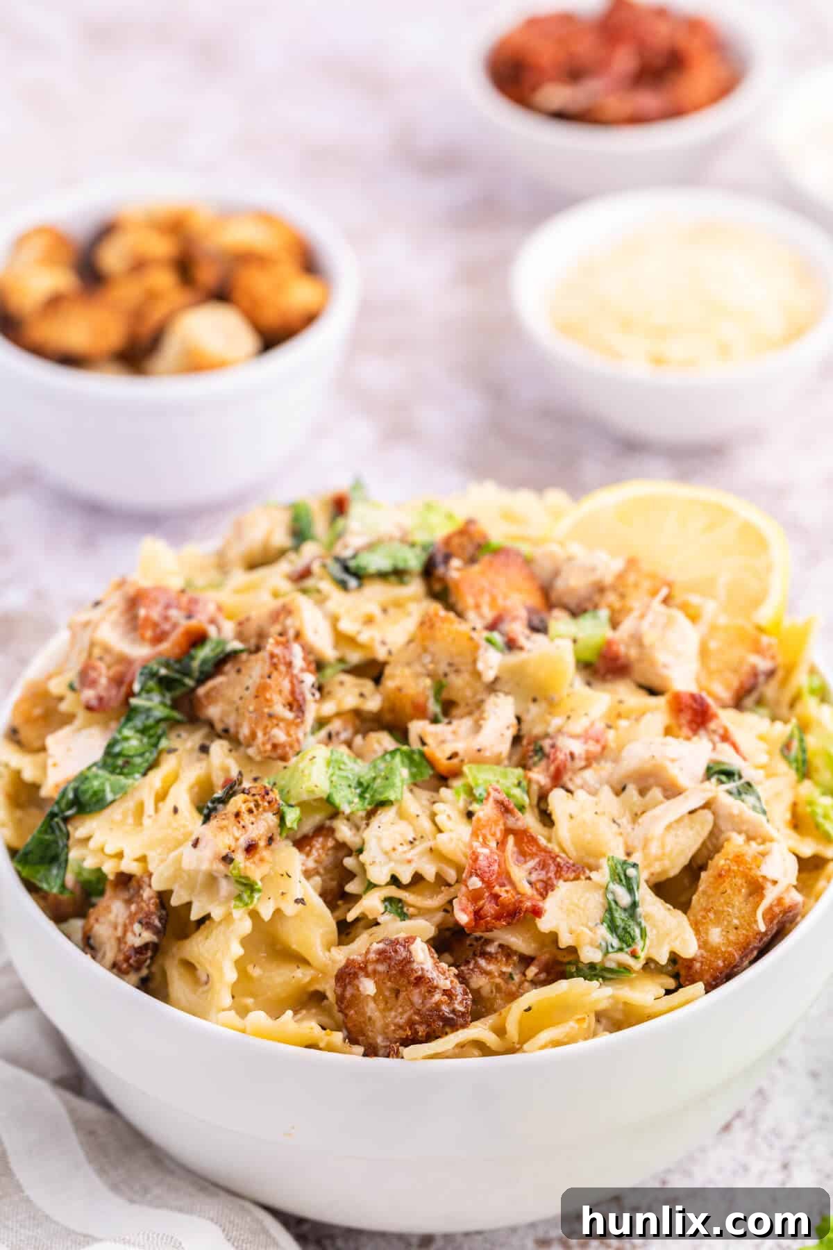 Signature Chicken Caesar Pasta 5 A simple white bowl filled with creamy Chicken Caesar Pasta Salad, showcasing its inviting texture and appetizing appearance.