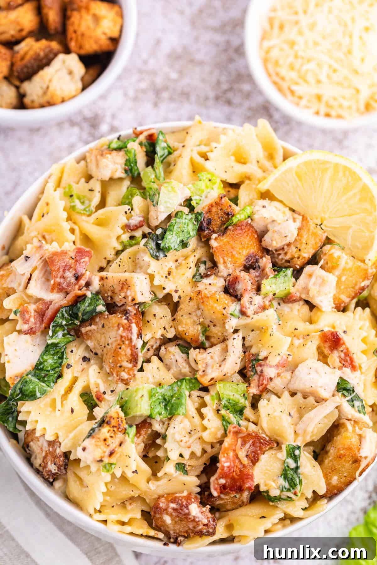 Signature Chicken Caesar Pasta 6 The Chicken Caesar Pasta Salad presented beautifully in a bowl, with extra croutons and Parmesan cheese sprinkled on top, ready for serving.