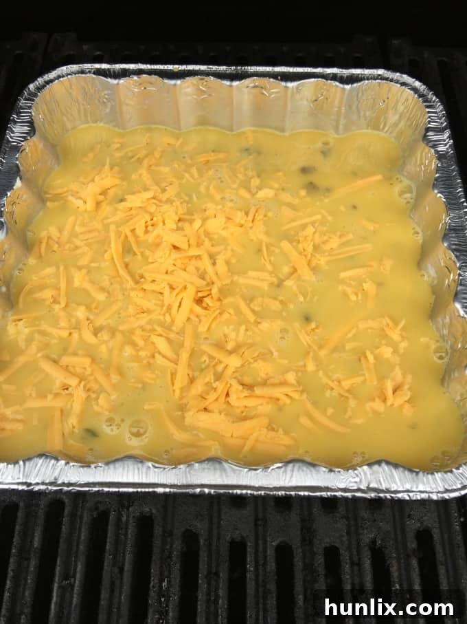 A carton of Burnbrae Farms Egg Creations Whole Eggs Mushroom & Spinach sits beside a bowl of freshly shredded cheddar cheese, showcasing the minimal and convenient ingredients needed for a delicious BBQ Eggs camping breakfast.