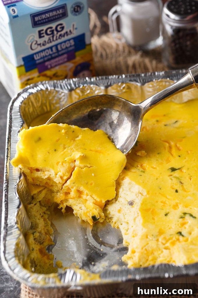 A full disposable foil pan brimming with perfectly cooked, fluffy, and cheesy BBQ Eggs, ready to be served buffet-style, showcasing a generous and satisfying camping breakfast for a group.