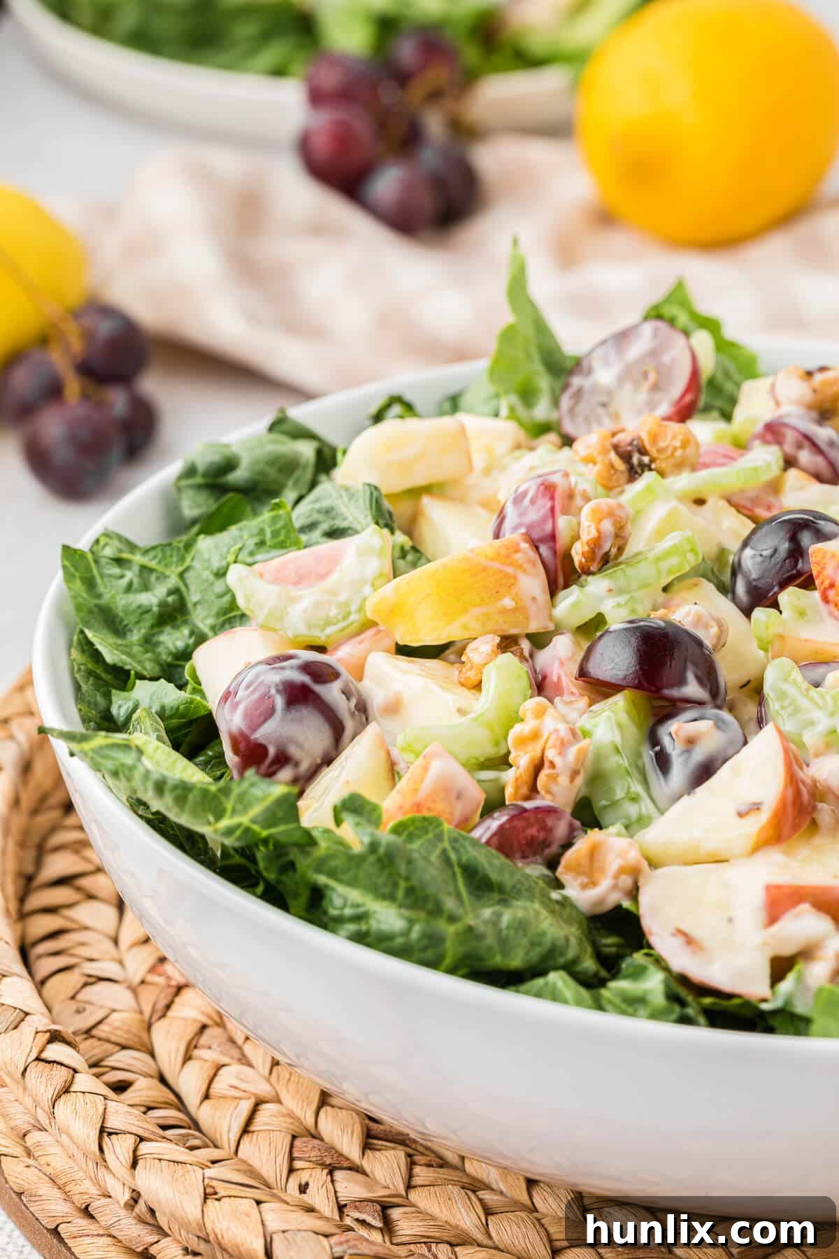 A close-up of a single serving bowl filled with Waldorf salad, garnished with a sprig of mint and a few extra walnuts, highlighting its inviting colors and textures on a pristine white background.