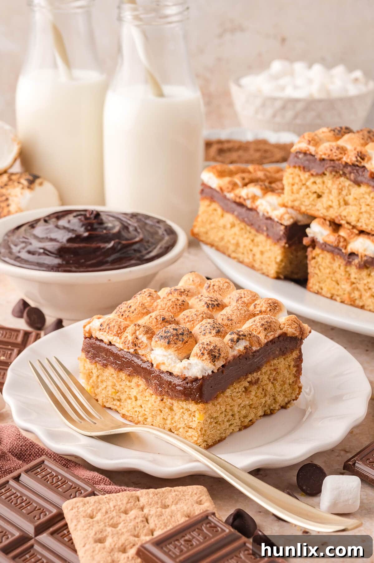 A slice of S'mores Cake on a white plate with a fork, showing the defined layers.