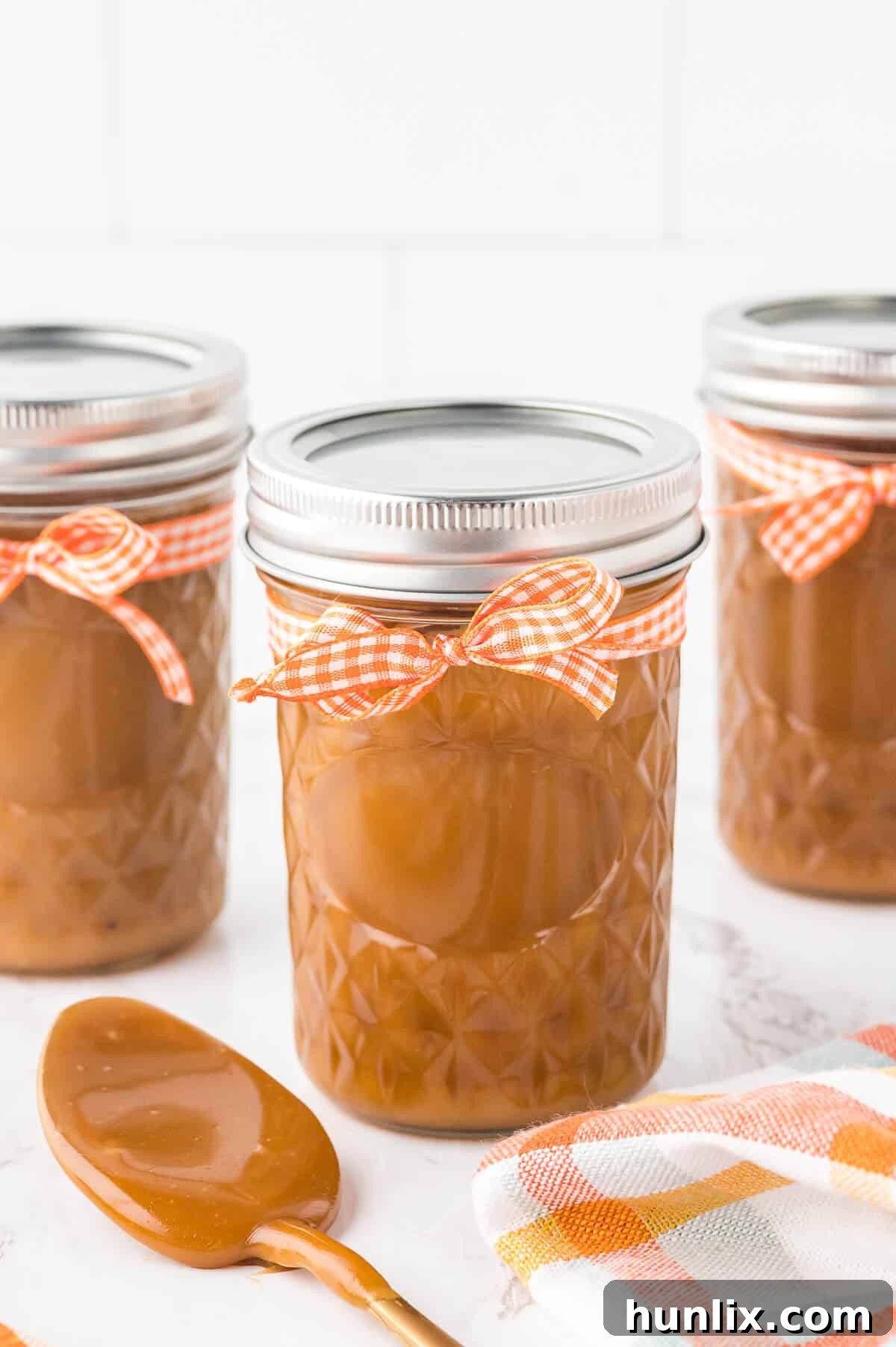 Two glass jars filled with homemade butterscotch sauce, showcasing its inviting golden color and smooth consistency.