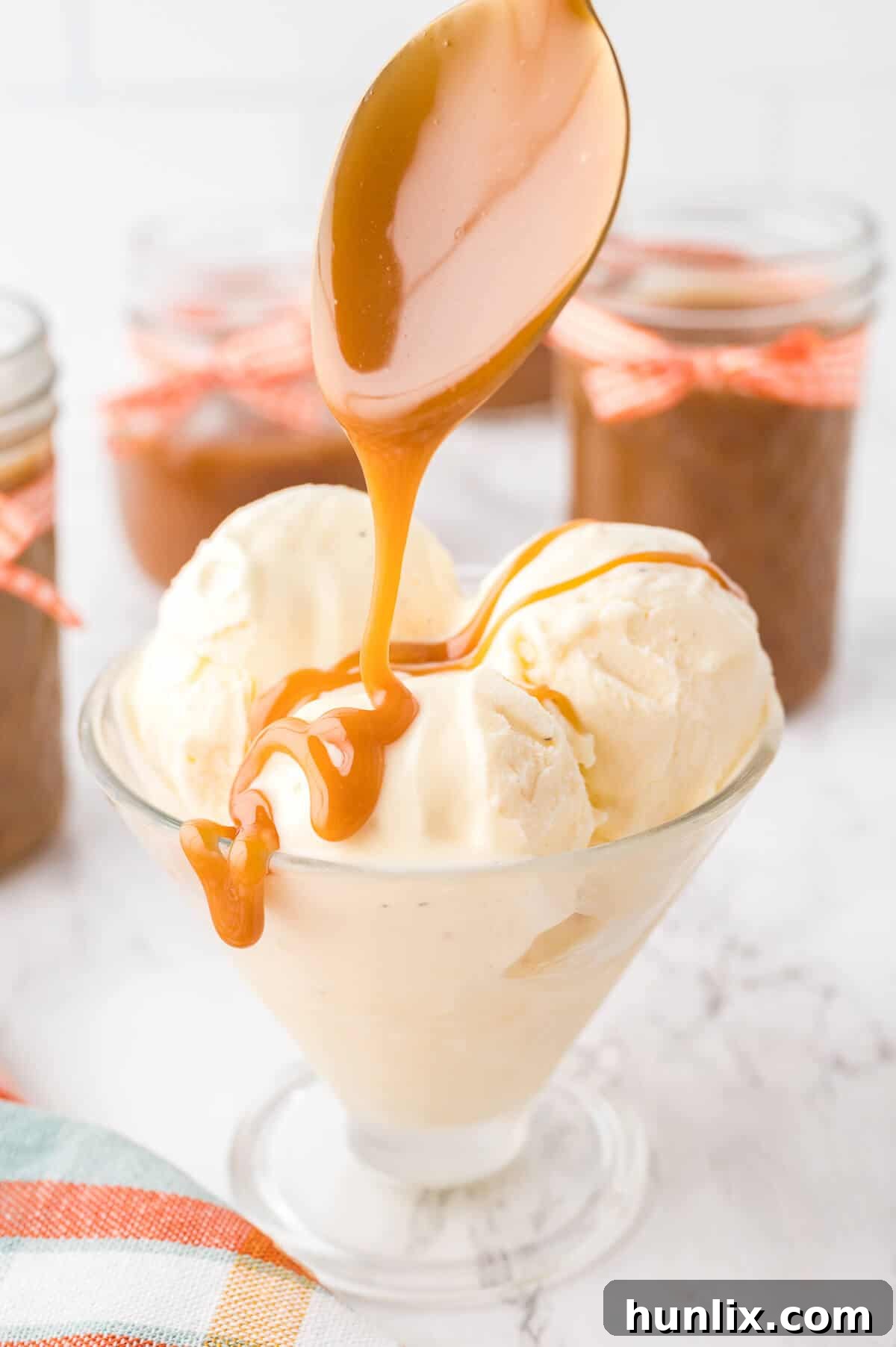 A generous drizzle of homemade butterscotch sauce flowing over a scoop of vanilla ice cream in a glass bowl.