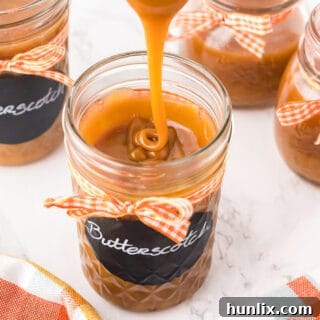 Homemade butterscotch sauce being drizzled into a jar, highlighting its rich texture.