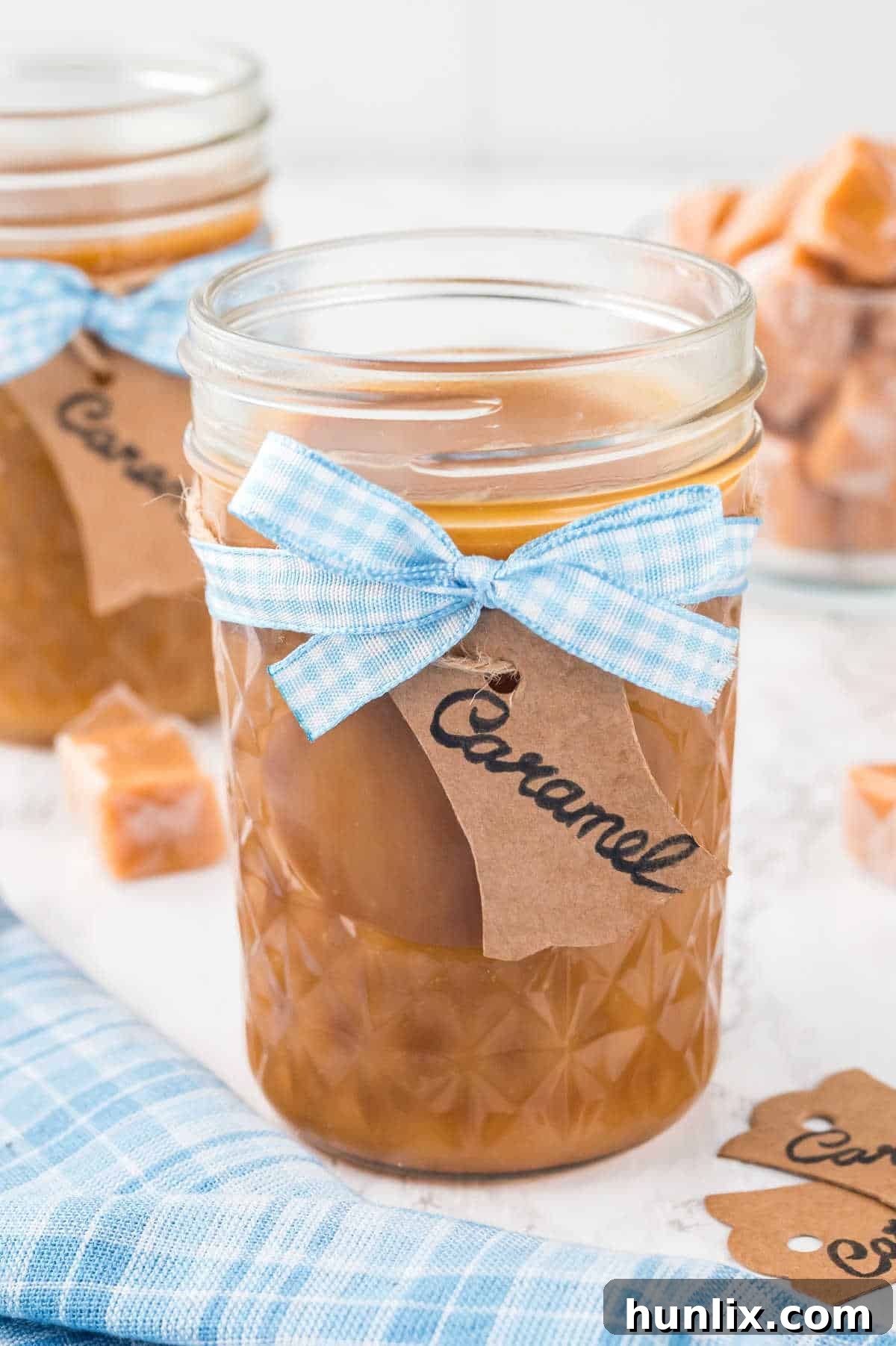 The homemade caramel sauce in a glass jar, tied with a blue ribbon, ready for gifting or serving.