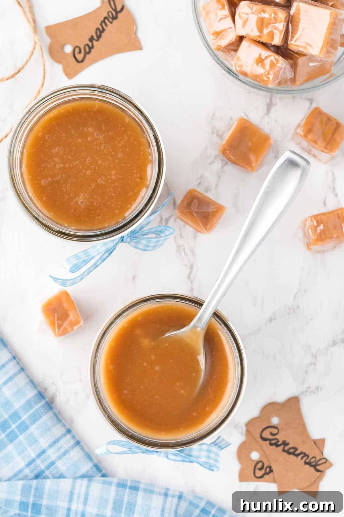 Two jars of homemade caramel sauce, one with a spoon, highlighting the rich amber color and smooth texture.
