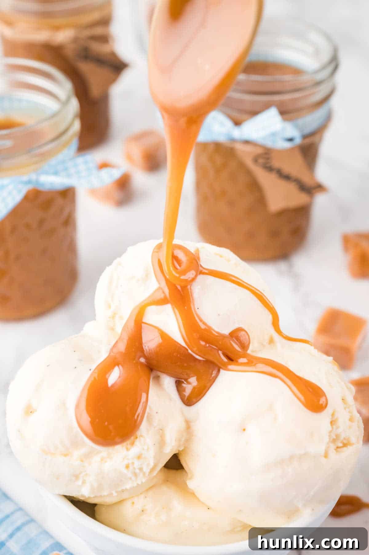 The homemade caramel sauce being poured over a bowl of creamy vanilla ice cream, creating a decadent dessert.