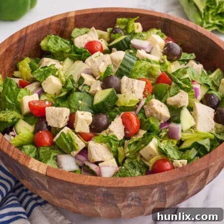 The Greek Chicken Salad in a wooden bowl on a white counter.