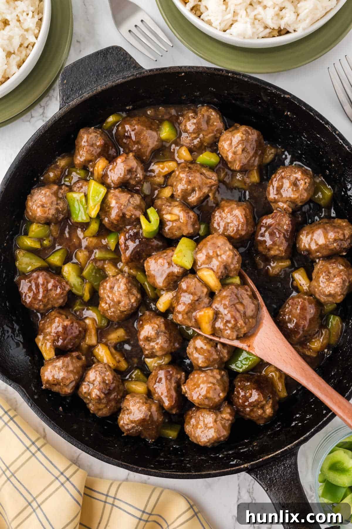 Waikiki meatballs in a skillet with a wooden spoon, ready to be served.