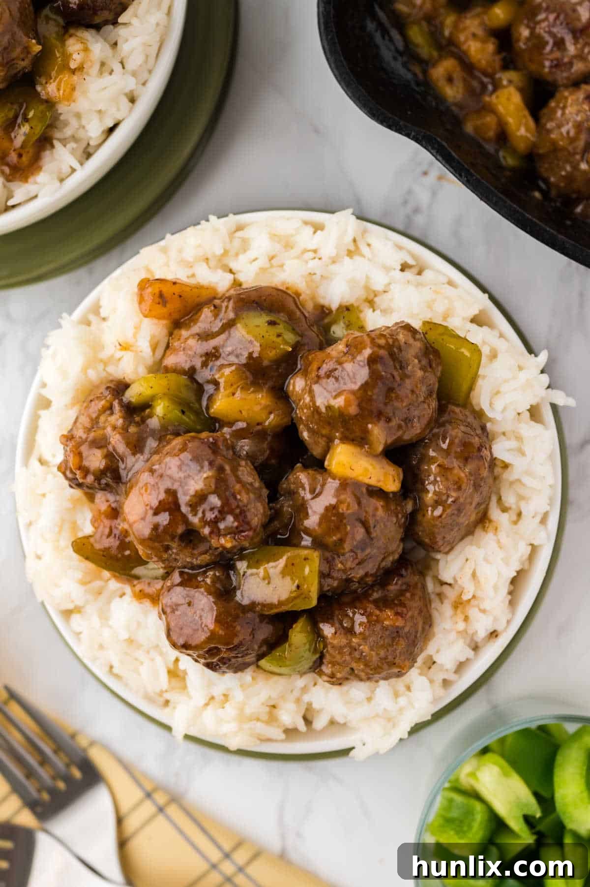 A plate of Waikiki meatballs served over a bed of white rice, garnished with fresh green onion.
