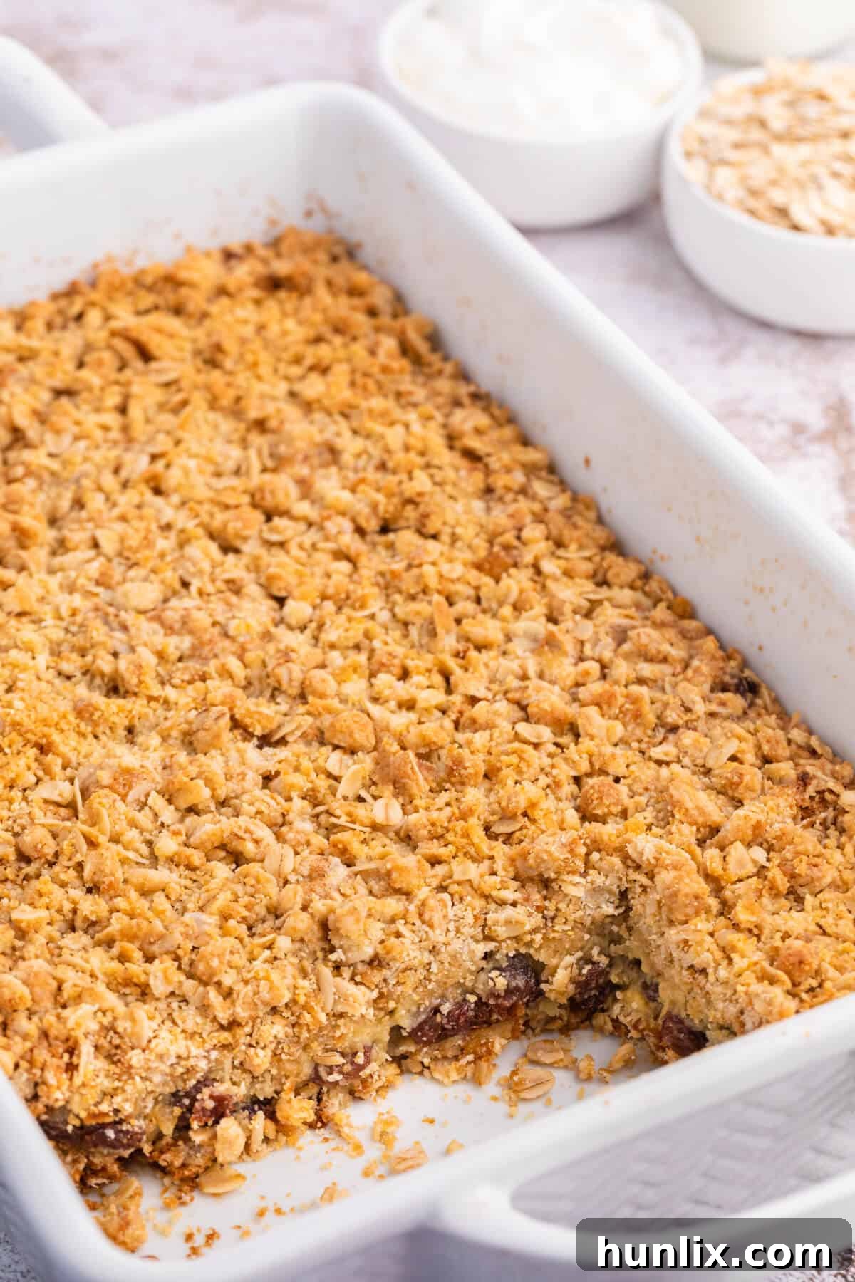 Sweet and Tangy Raisin Bars 2 Sour cream raisin bars in a pan with a few squares cut out.