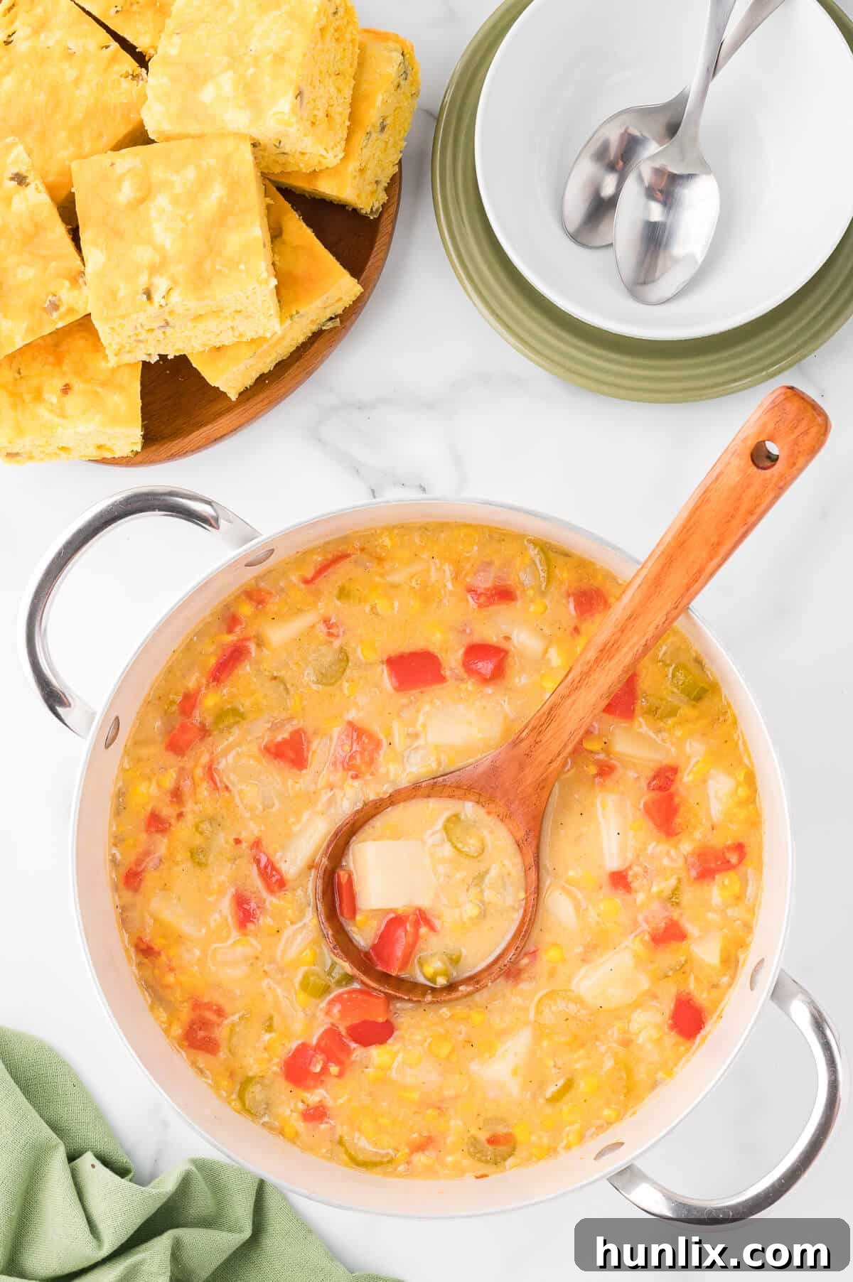 Sunshine Corn Chowder 2 A pot of creamy corn chowder with a wooden ladle, showcasing its rich texture and vibrant ingredients.