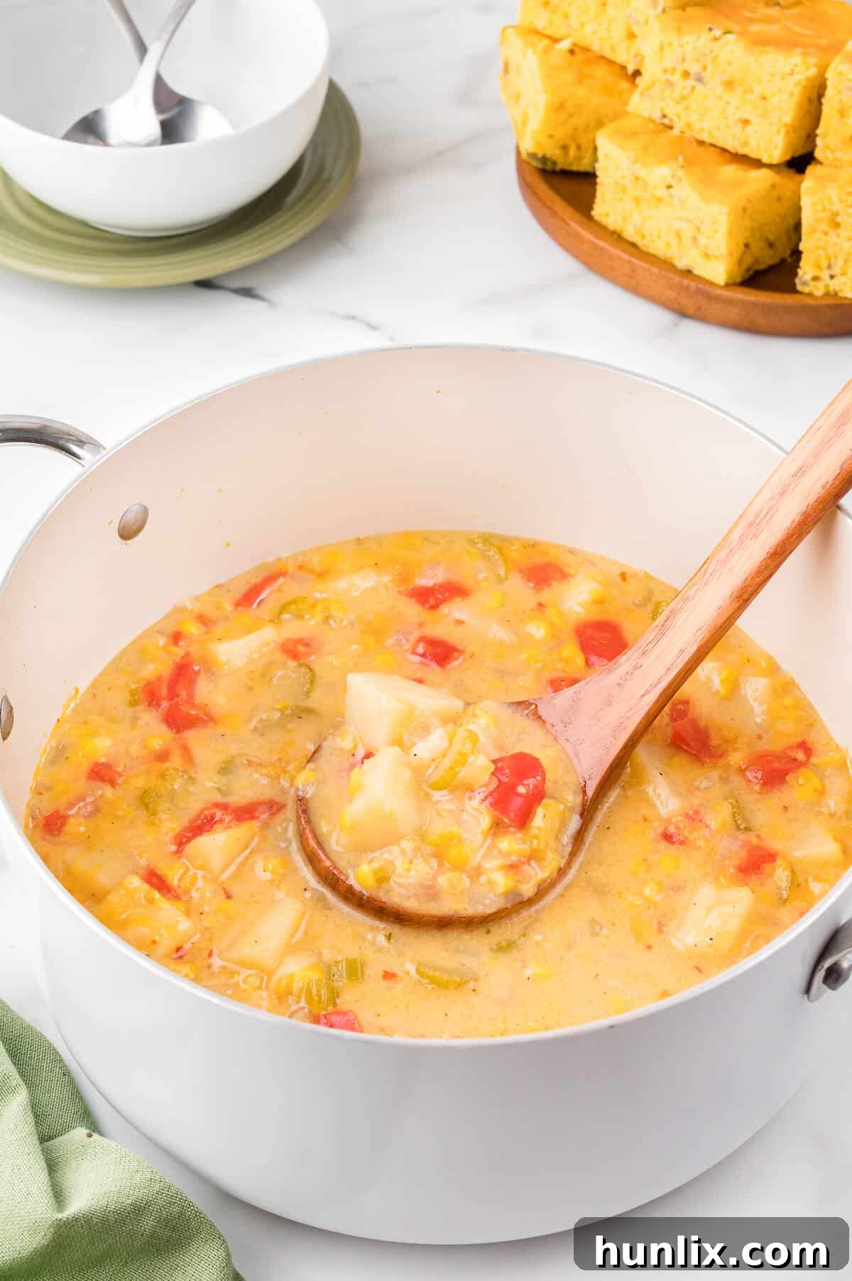 Sunshine Corn Chowder 6 A pot of creamy corn chowder with a wooden ladle resting inside, ready to be served, highlighting its rich and inviting appearance.
