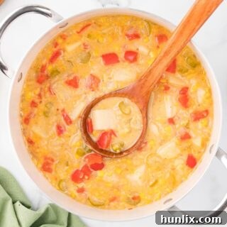 A pot of corn chowder with a wooden ladle, ready to be served, showcasing its rich texture.