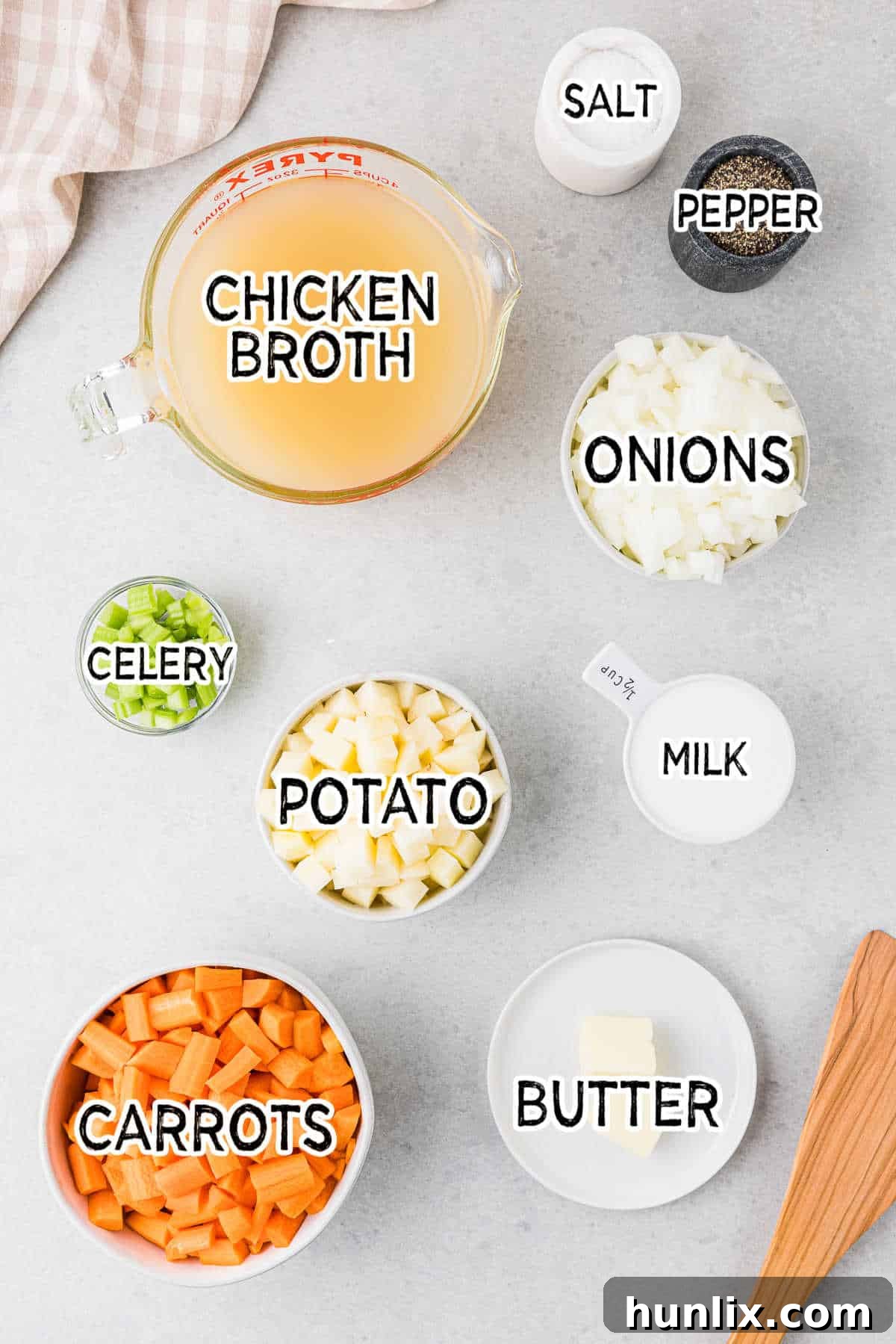 All the fresh ingredients for cream of carrot soup laid out: carrots, potato, celery, onion, butter, chicken broth, milk, salt, and pepper.