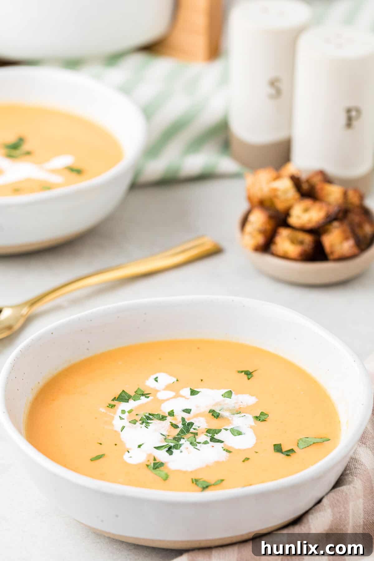 A minimalist shot of a single white bowl of rich, creamy carrot soup.
